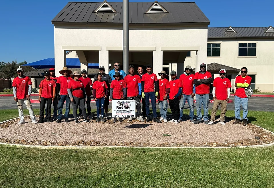 American Homes Roofing crew in red company shirts, lined up behind a company yard sign.