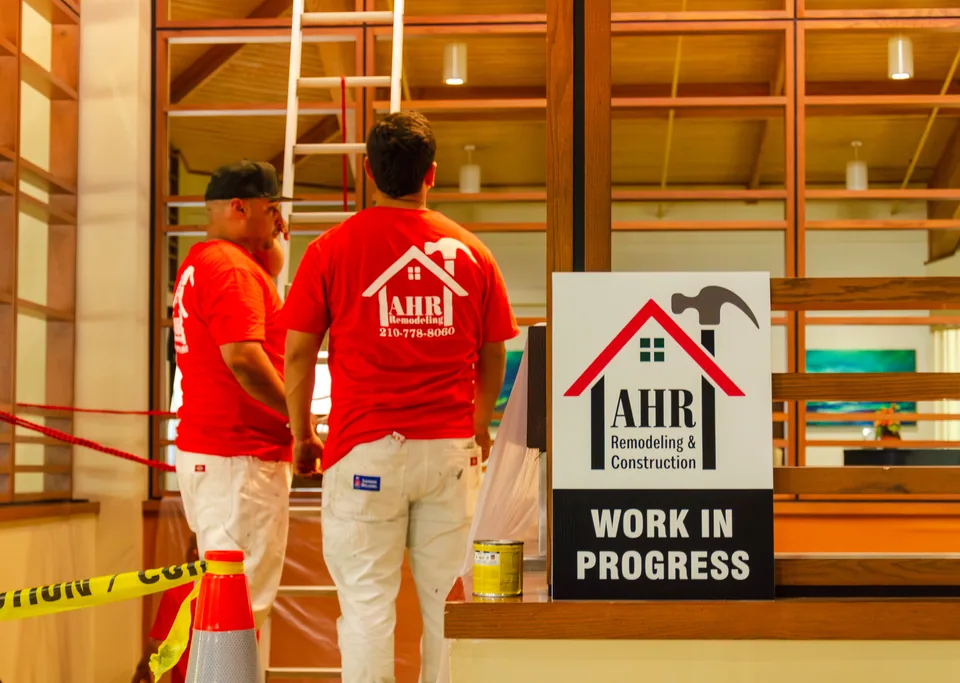 AHR crew working inside a commercial building, with the work area marked off by caution tape and a 'Work in progress' sign.
