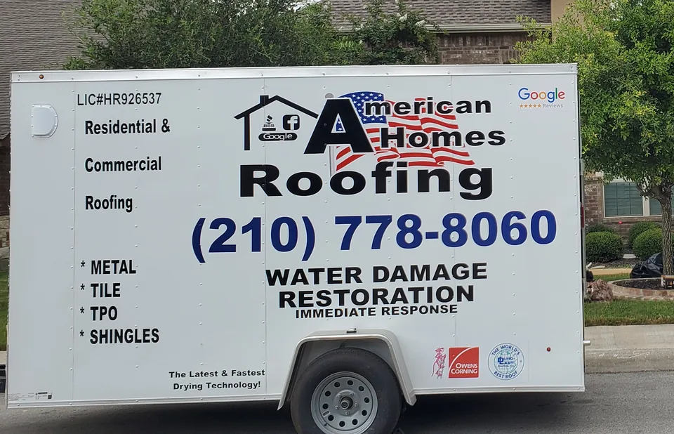 Side of an American Homes Roofing trailer lettered for residential and commercial roofing, with the company phone number.
