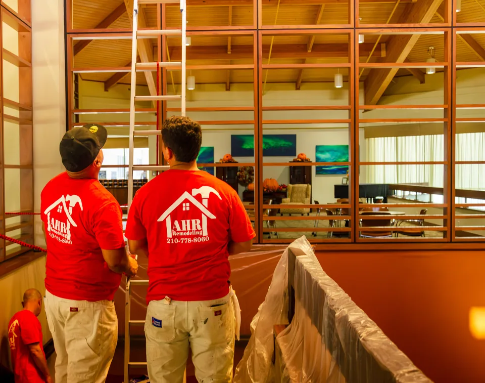 Three AHR crew members inside a commercial building, looking up at the wood screens they are working on, with the stair rail wrapped in plastic.